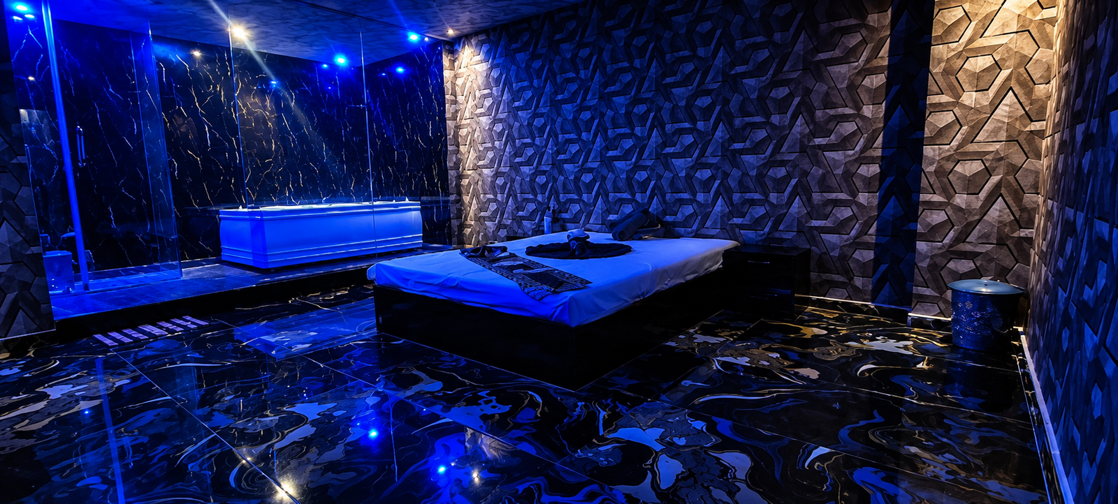 Private VIP suite with Jacuzzi, massage bed and blue ambient lighting at UNIQ International Thai Spa Marathahalli — black marble interior and premium spa setting