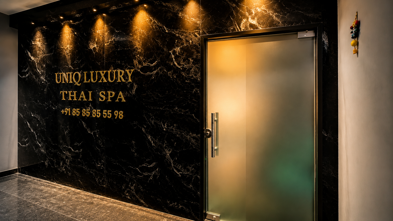 UNIQ Luxury Thai Spa entrance — black marble wall with gold lettering and frosted glass door at Marathahalli Outer Ring Road Bengaluru