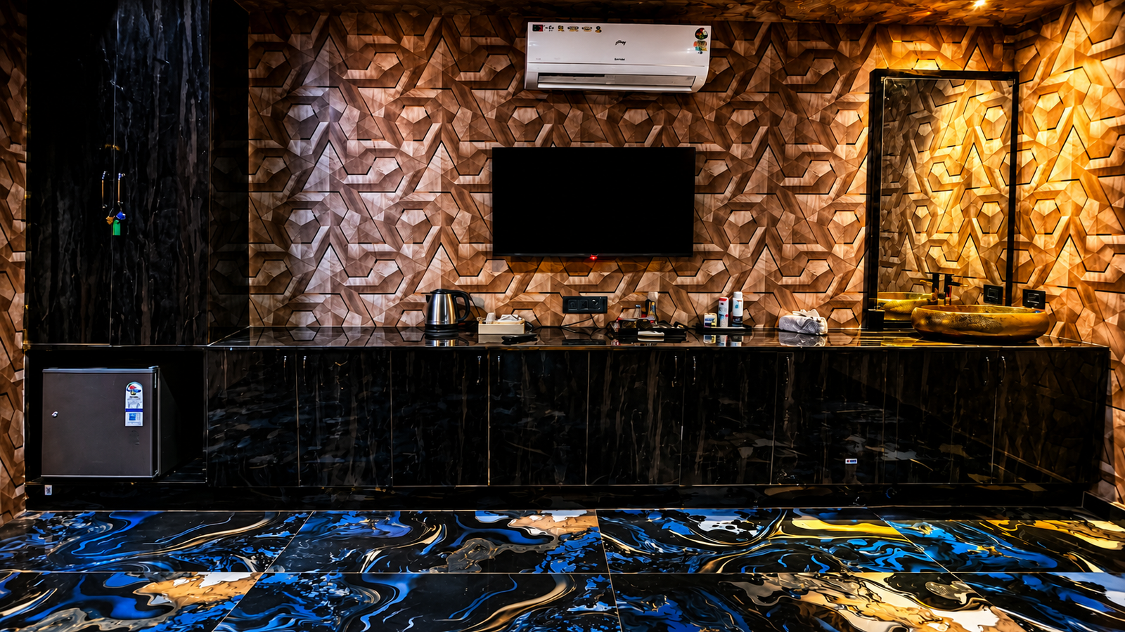 VIP suite amenity detail at UNIQ International Thai Spa Marathahalli — geometric patterned wall, mounted TV, kettle, mini-fridge, gold basin and swirling marble floor