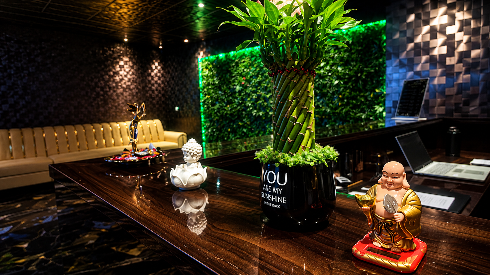 UNIQ International Thai Spa reception lobby — dark wood desk, Buddha statue, bamboo plant, golden sofa and green living wall in Marathahalli Bengaluru