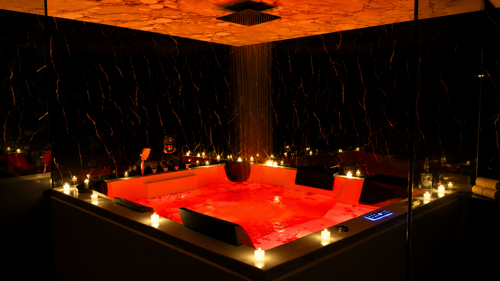 Red and orange rain-shower Jacuzzi at UNIQ International Thai Spa Marathahalli — warm chromotherapy lighting and premium rain-shower feature inside the private Jacuzzi suite